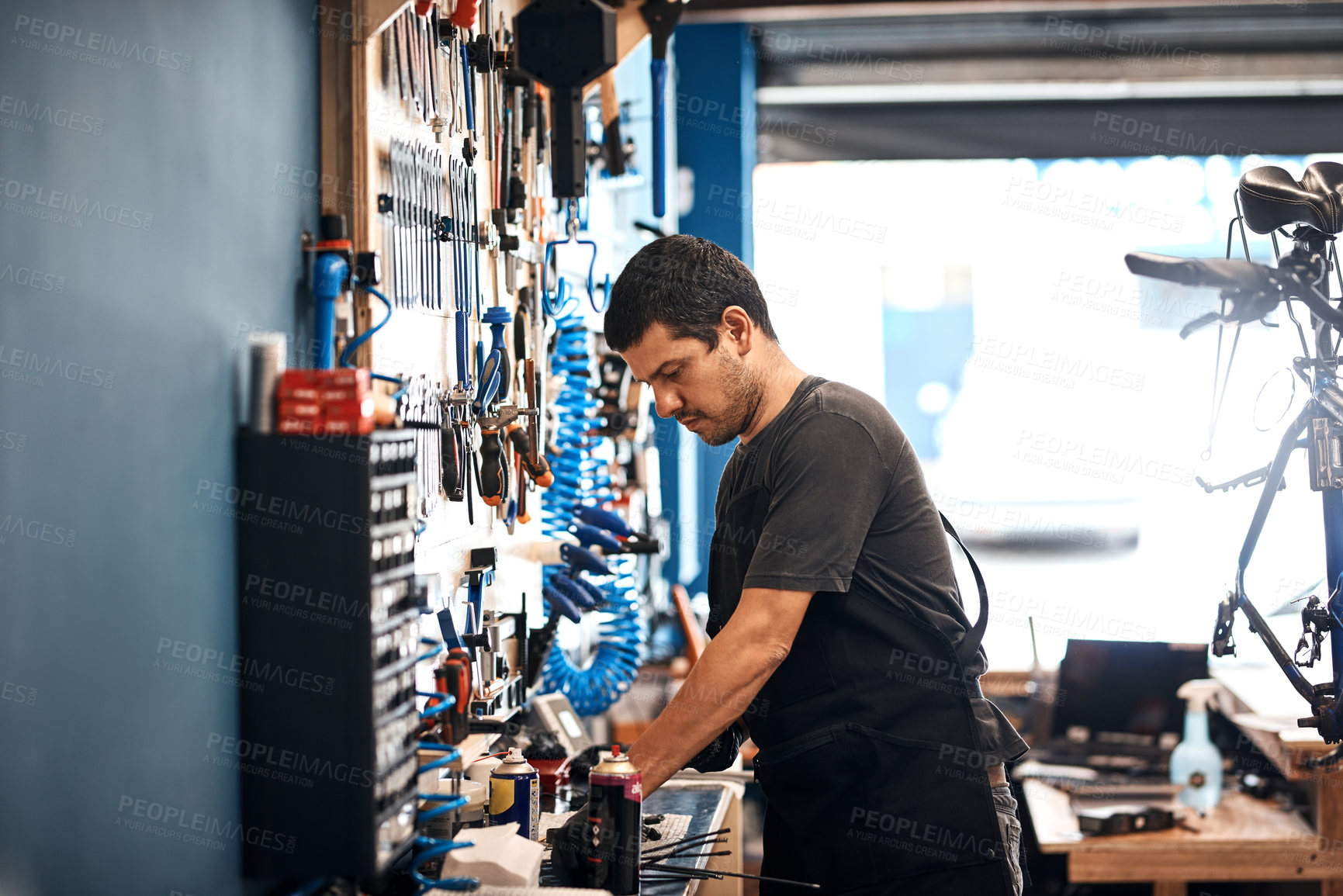 Buy stock photo Shot of a man working in a bicycle repair shop