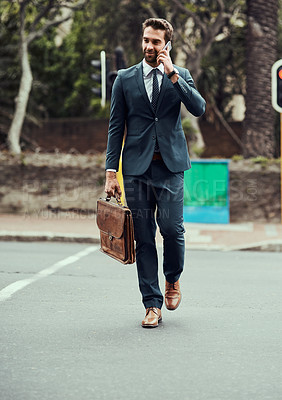 Buy stock photo Shot of a handsome young businessman talking on a cellphone while out in the city