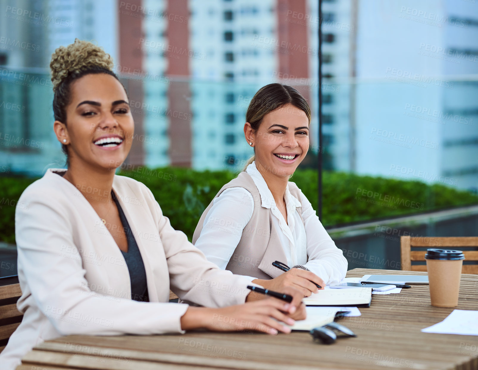 Buy stock photo Cropped portrait of two attractive young businesswomen sitting in the boardroom during a meeting