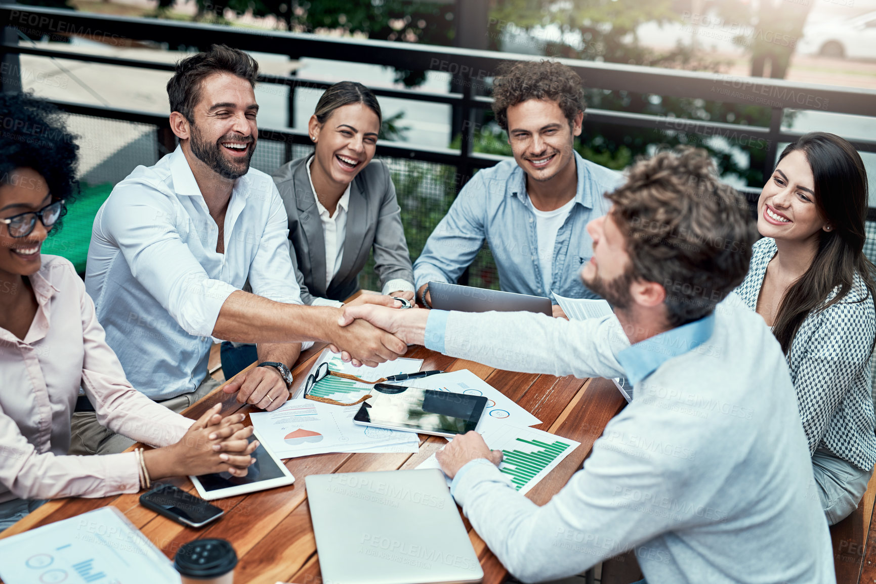 Buy stock photo Shot of businesspeople shaking hands during a meeting at a cafe