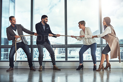 Buy stock photo Shot of a group of businesspeople pulling on a rope during tug of war in an office