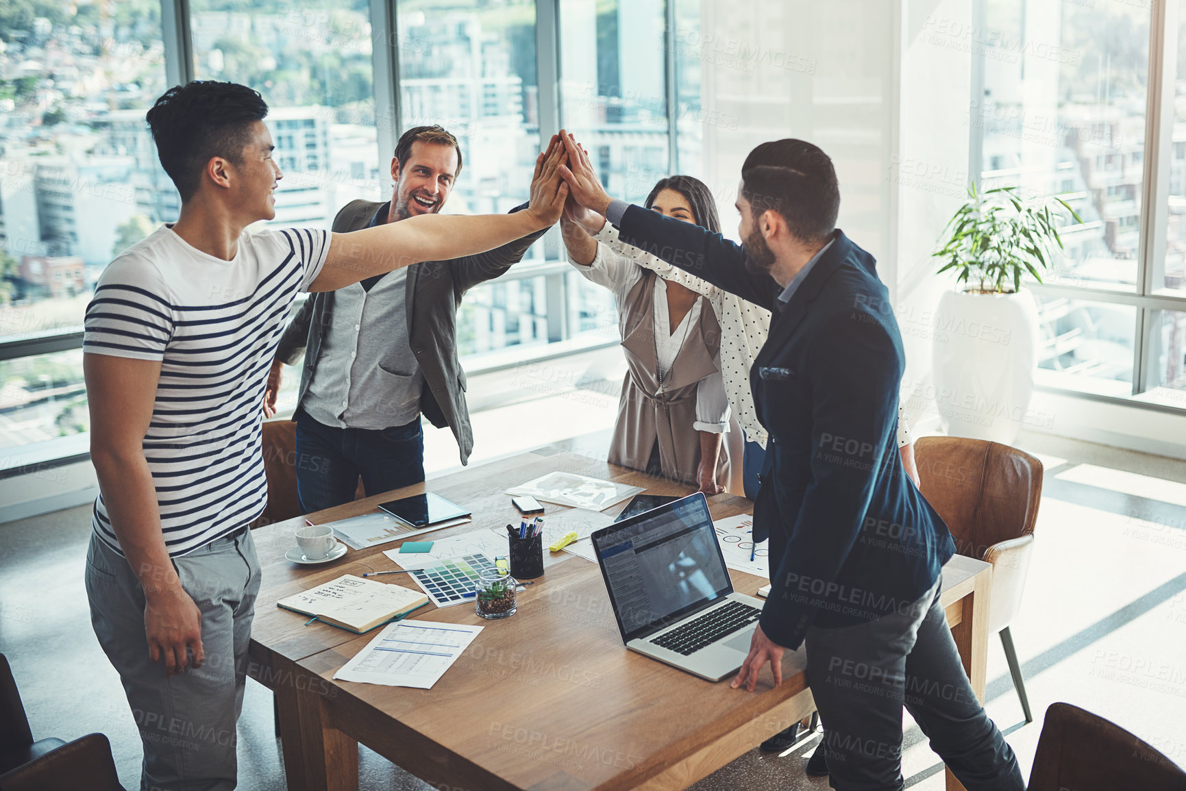 Buy stock photo Shot of a diverse group of businesspeople high fiving in an office