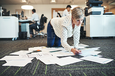 Buy stock photo Shot of a businesswoman working with paperwork on the floor in the office
