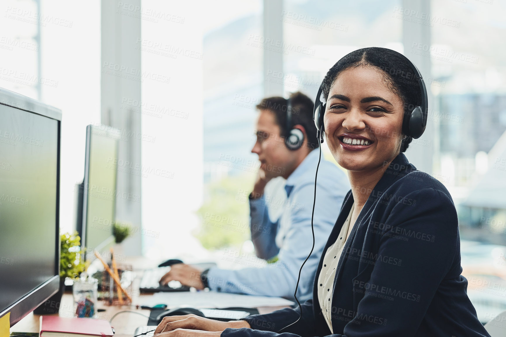 Buy stock photo Portrait of happy call center agent working in a busy office, assisting clients and providing good customer service. Young, smiling and cheerful professional excited to offer support or help on calls