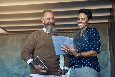 Buy stock photo Cropped shot of two creative businesspeople looking over some paperwork in the office