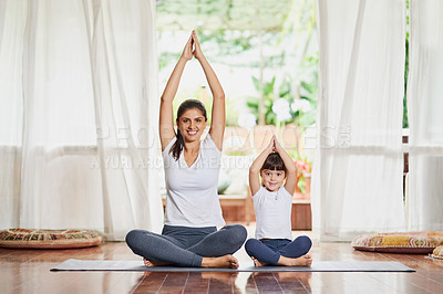 Buy stock photo Portrait of a focused young mother and daughter doing a yoga pose together with their arms raised above their heads