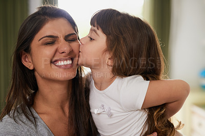 Buy stock photo Shot of a little girl giving her mother a kiss on the cheek at home