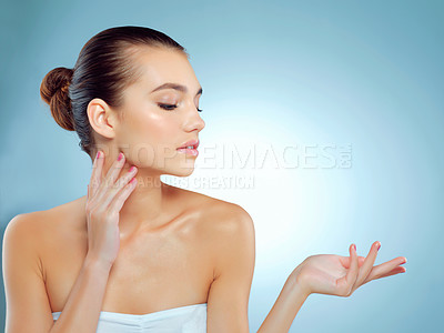 Buy stock photo Studio shot of a beautiful young woman gesturing towards copy space against a blue background