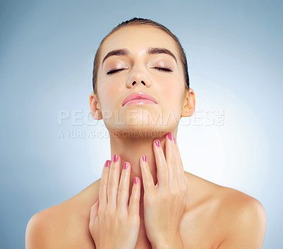 Buy stock photo Studio shot of a beautiful young woman feeling her skin against a blue background