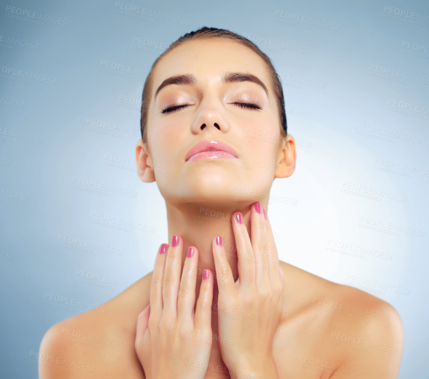 Buy stock photo Studio shot of a beautiful young woman feeling her skin against a blue background