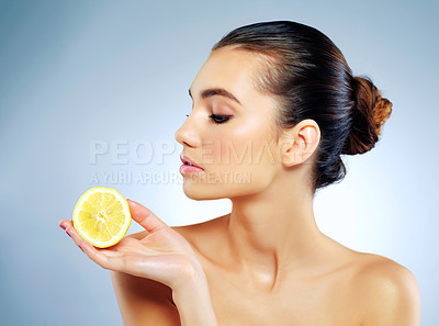 Buy stock photo Studio shot of a beautiful young woman holding a lemon against a blue background