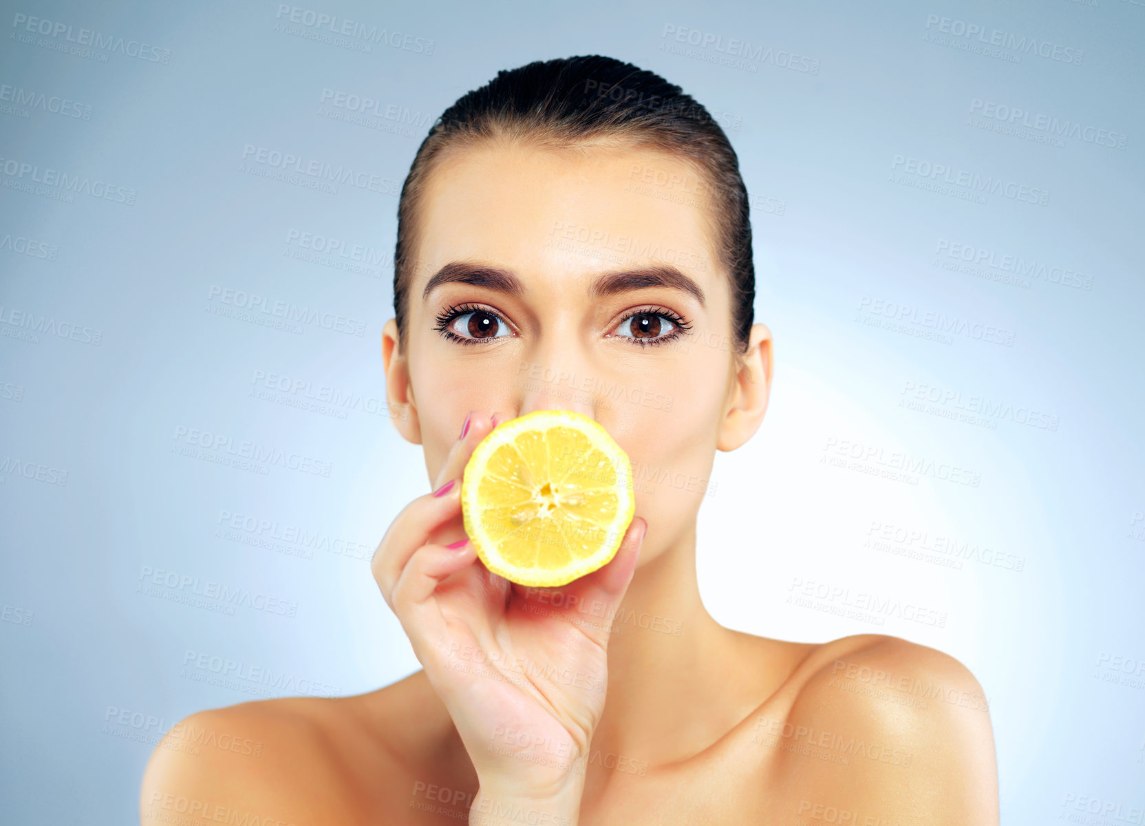 Buy stock photo Girl, portrait and lemon on mouth in studio for skincare or natural beauty, facial treatment and organic cosmetics ingredient. Woman, blue background and fruit by lips for quiet, secret and vitamin c