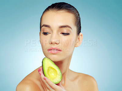 Buy stock photo Studio shot of a beautiful young woman holding an avocado against a blue background