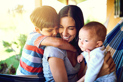 Buy stock photo Shot of a cheerful mother relaxing on a hammock with her two little boys outside at home during the day