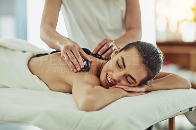 Buy stock photo Shot of an attractive young woman getting a hot stone massage at a beauty spa
