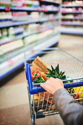 Buy stock photo Cropped shot of a woman pushing a trolley while shopping at a grocery store