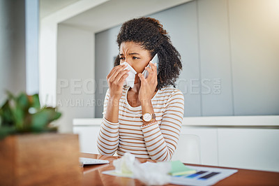 Buy stock photo Shot of a young woman blowing her nose while working at home