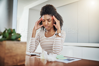 Buy stock photo Shot of a young woman suffering with a headache while working at home