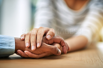 Buy stock photo Cropped shot of two unrecognizable people holding hands while being seated at a table inside during the day