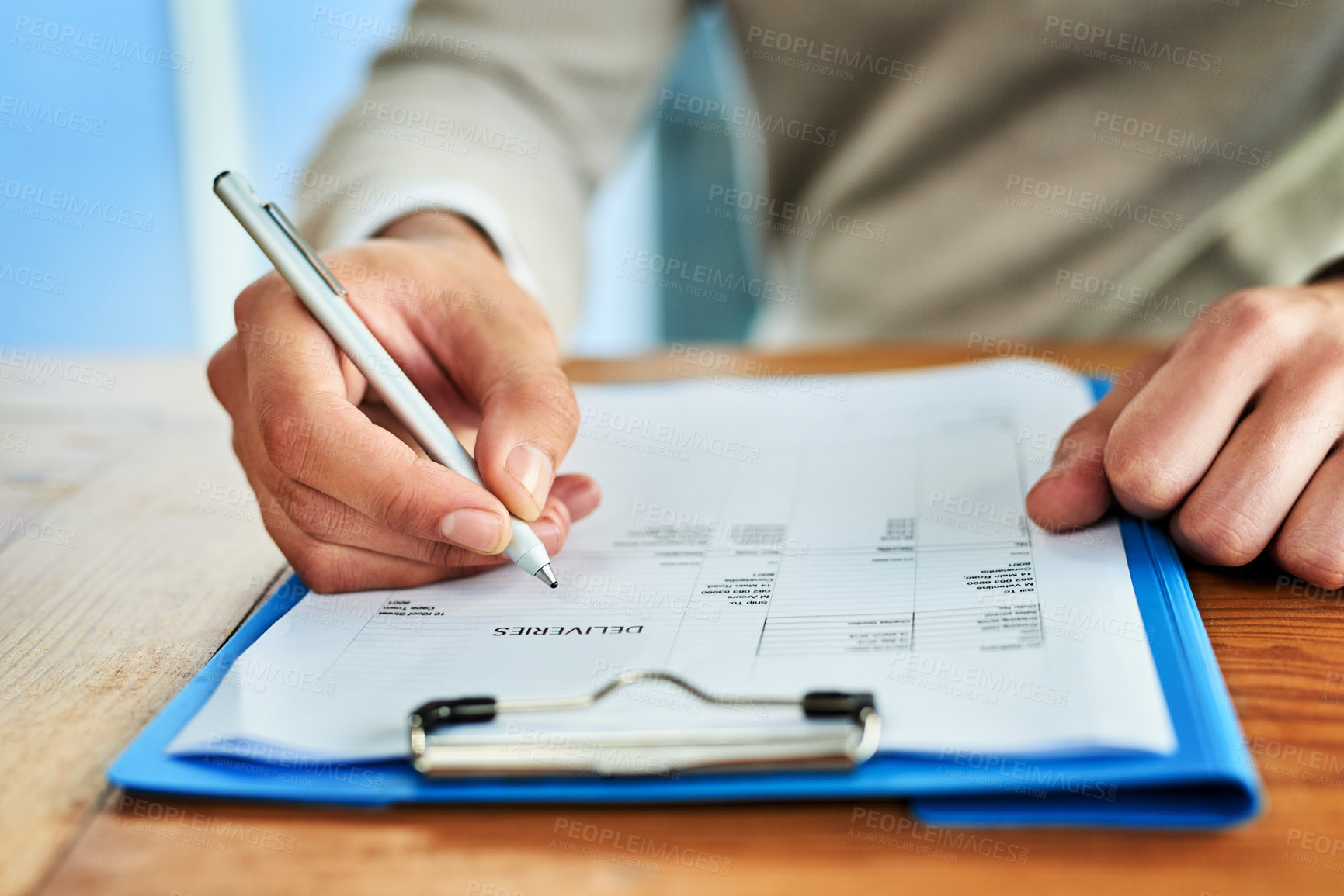 Buy stock photo Cropped shot of an unrecognizable businessman filling out paperwork on a clipboard while sitting at a table in an office