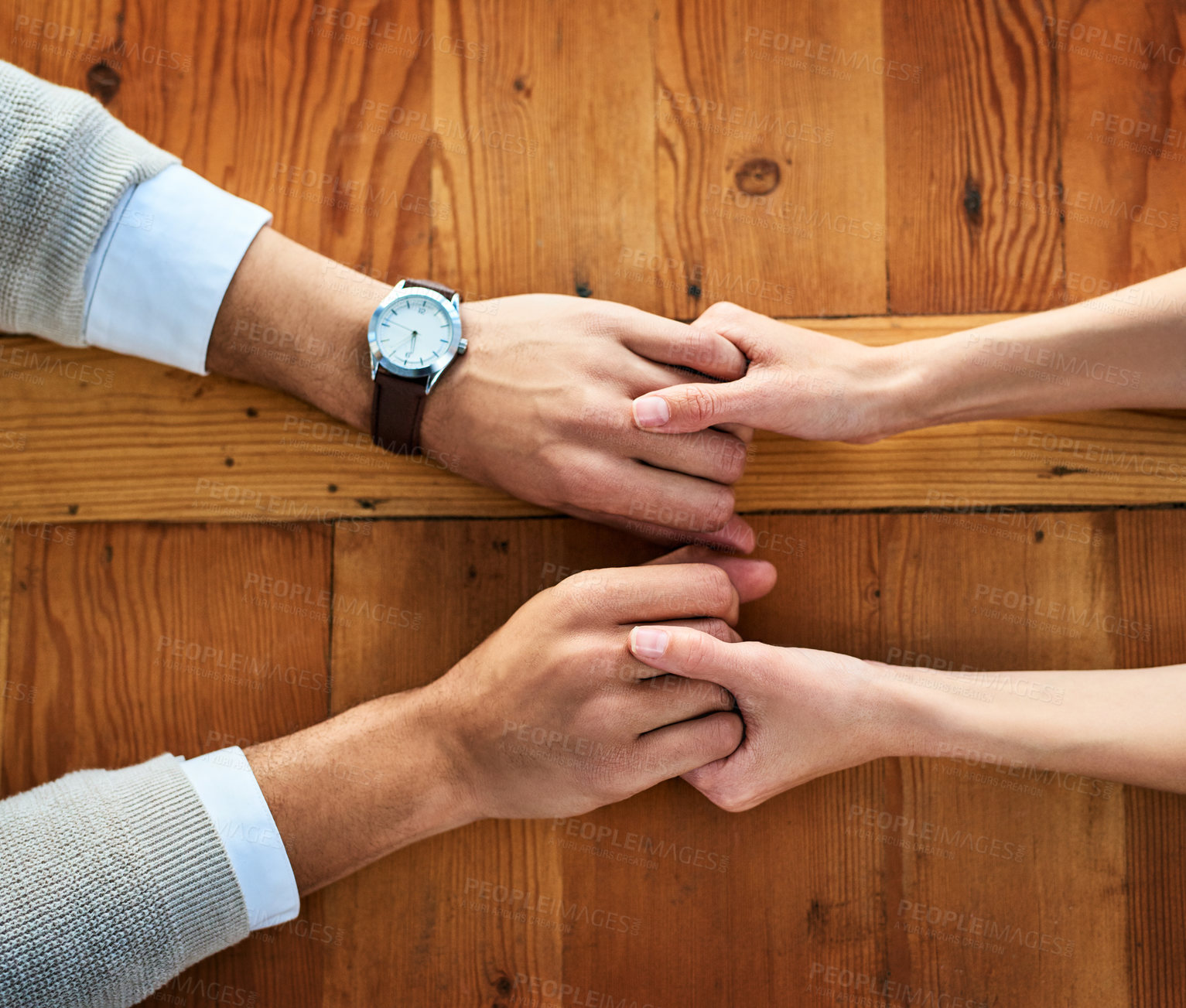 Buy stock photo Cropped shot of two unrecognizable people holding hands while being seated at a table inside during the day