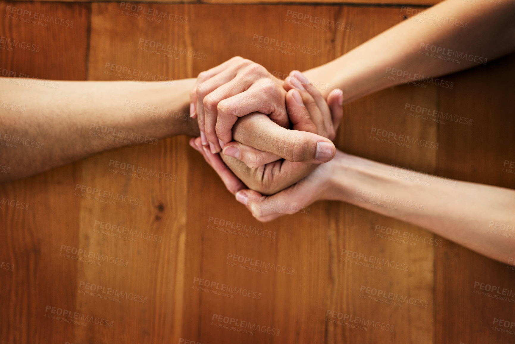 Buy stock photo Cropped shot of two unrecognizable people holding hands while being seated at a table inside during the day