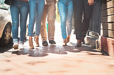 Buy stock photo Low angle shot of a group of unrecognizable people walking together down a street outside during the day