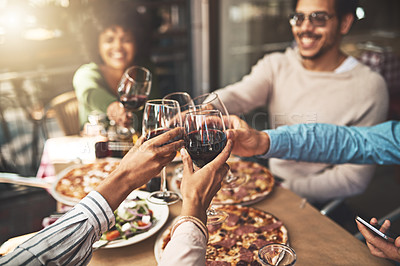 Buy stock photo Shot of a group of cheerful young friends having a celebratory toast with wine at dinner inside of a restaurant