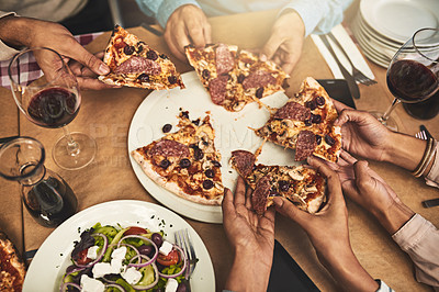 Buy stock photo High angle shot of a group of unrecognizable people's hands each grabbing a slice of pizza while being seated at a restaurant
