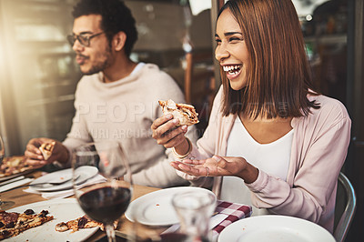 Buy stock photo Shot of a cheerful young woman and man eating pizza together while being seated at a table inside of a restaurant