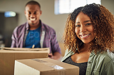Buy stock photo Portrait of a cheerful young couple carrying boxes together to move into their new home inside during the day