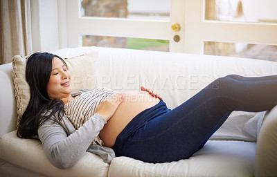 Buy stock photo Cropped shot of an attractive young pregnant woman relaxing on the sofa at home