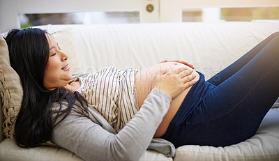 Buy stock photo Cropped shot of an attractive young pregnant woman relaxing on the sofa at home