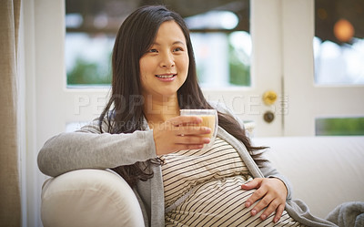 Buy stock photo Shot of an attractive young pregnant woman drinking an iced coffee while relaxing on the sofa at home