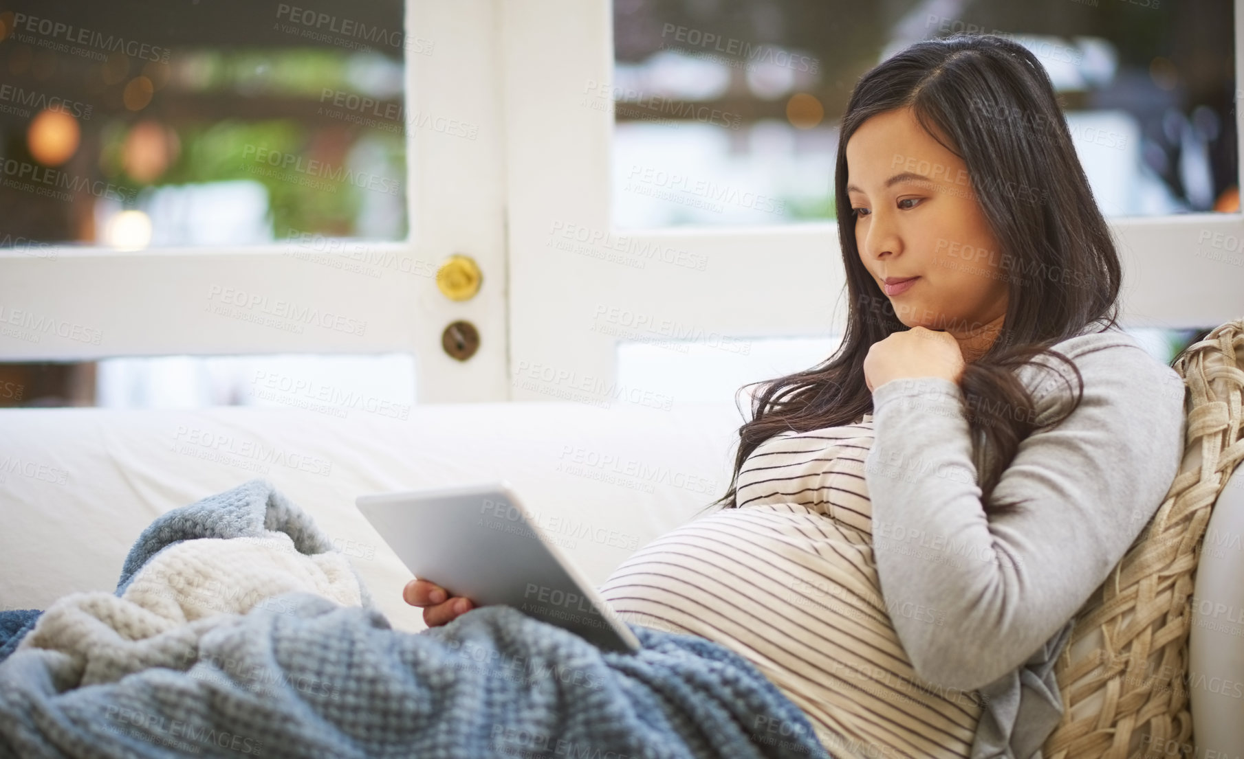 Buy stock photo Shot of a pregnant woman using a digital tablet at home