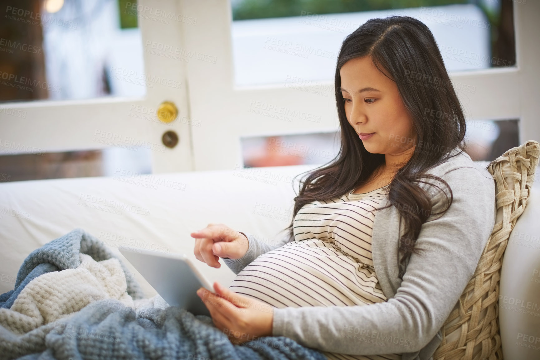 Buy stock photo Shot of a pregnant woman using a digital tablet at home