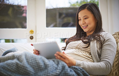 Buy stock photo Shot of a pregnant woman using a digital tablet at home