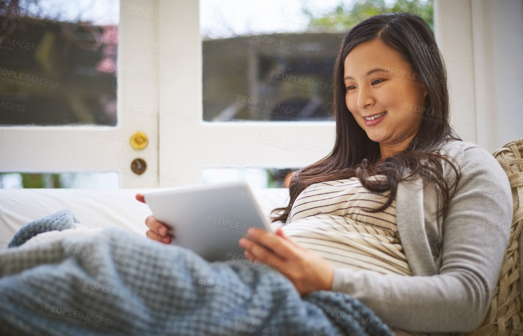 Buy stock photo Shot of a pregnant woman using a digital tablet at home