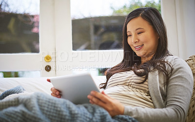 Buy stock photo Shot of a pregnant woman using a digital tablet at home