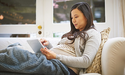 Buy stock photo Shot of a pregnant woman using a digital tablet at home