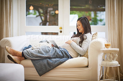 Buy stock photo Shot of a pregnant woman using a digital tablet at home