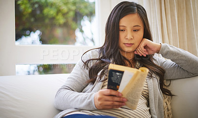 Buy stock photo Shot of a pregnant woman reading a book at home