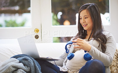 Buy stock photo Shot of a pregnant woman wearing headphones over her belly at home