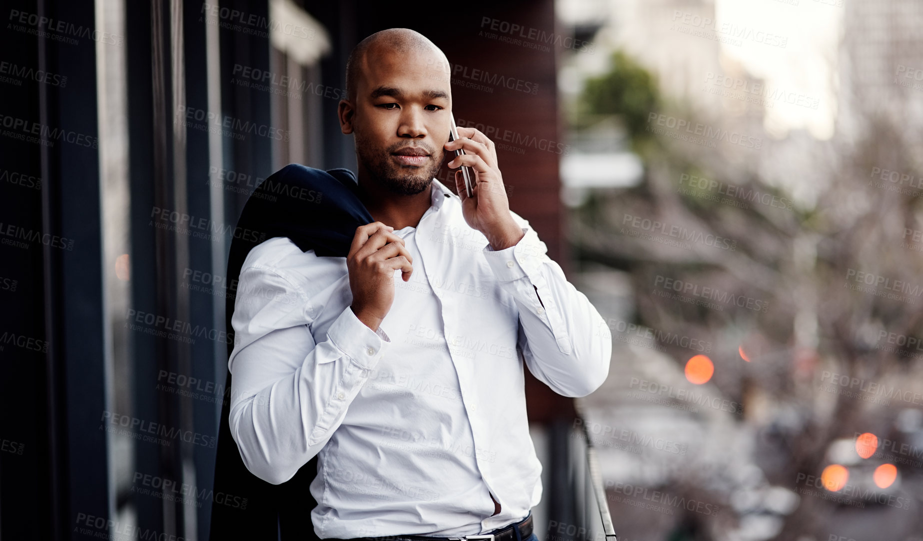 Buy stock photo Shot of a handsome young businessman talking on a cellphone outside his office