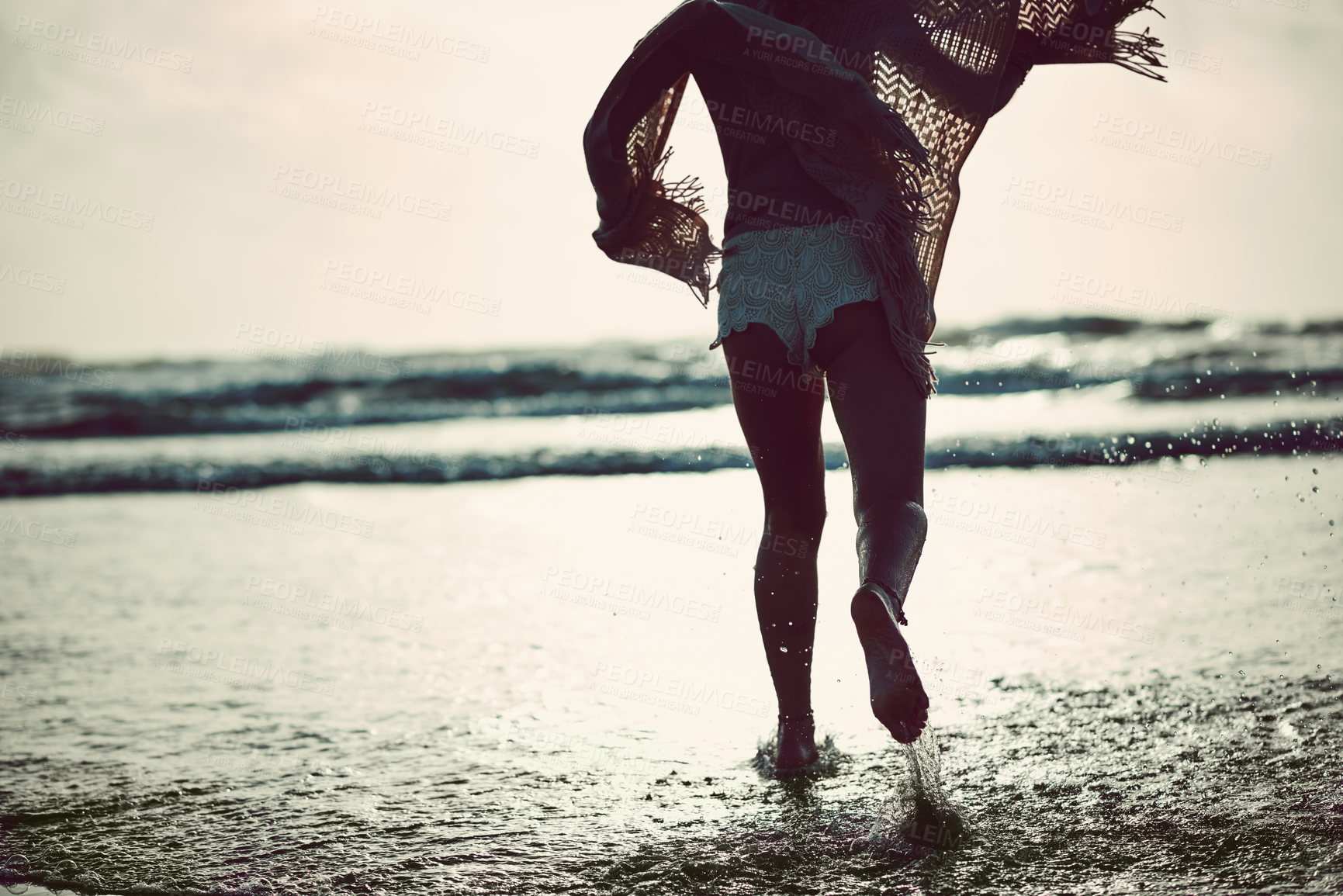 Buy stock photo Rearview shot of an unrecognizable woman spending a day at the beach