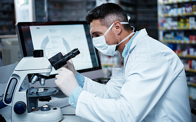 Buy stock photo Shot of a mature man using a microscope while conducting pharmaceutical research
