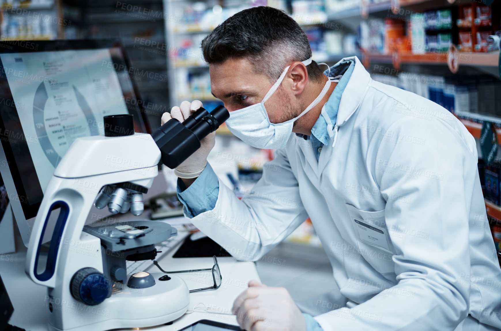 Buy stock photo Shot of a mature man using a microscope while conducting pharmaceutical research