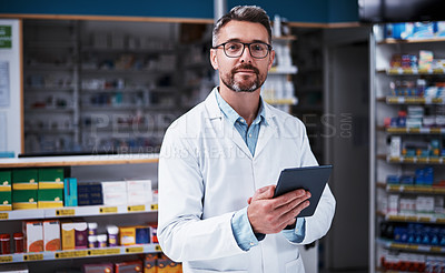 Buy stock photo Portrait of a handsome mature pharmacist using a digital tablet in a pharmacy