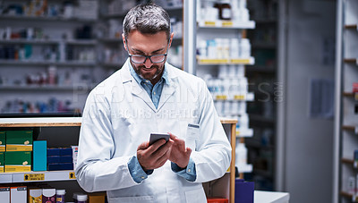 Buy stock photo Shot of a mature pharmacist using a cellphone in a pharmacy