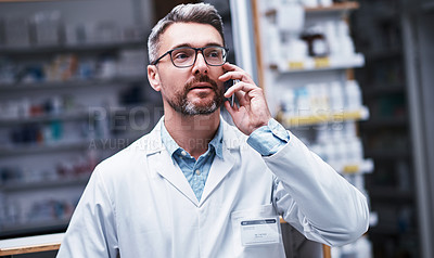Buy stock photo Shot of a mature pharmacist talking on a cellphone in a pharmacy
